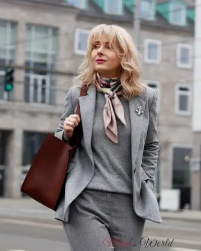 Frau in grauem Business-Anzug mit Tasche.
