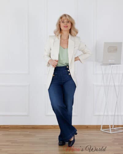 Frau in Jeans und weißem Blazer posiert.