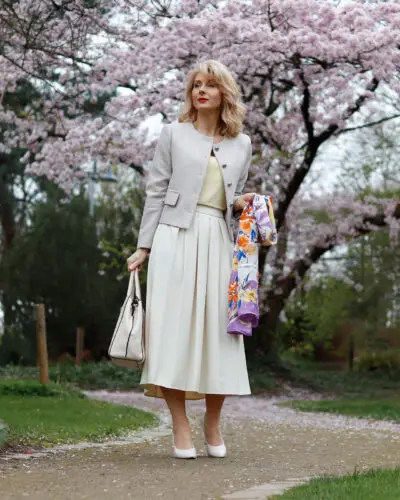 Woman posing with cherry blossoms in background.