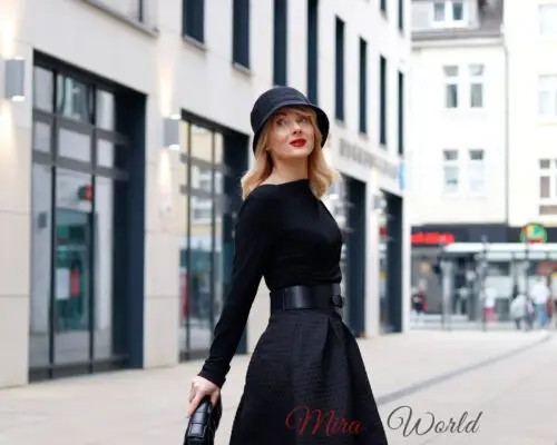 Woman in stylish hat and black outfit outdoors.