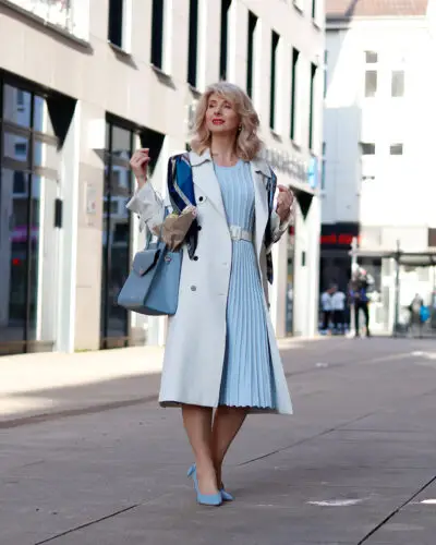 Woman in chic blue outfit on city sidewalk.