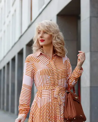 Woman in striped dress with purse outdoors.